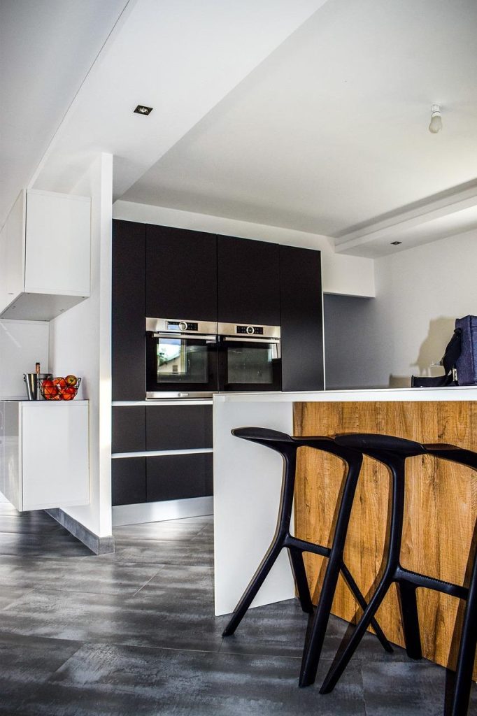 Moderne industriële keuken met zwarte kasten, hout en metalen elementen op gietvloer